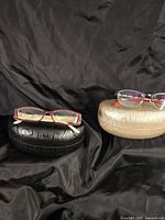 Both eyeglass frames on separate hard cases
