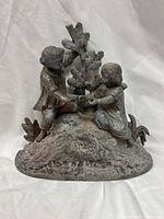 Front view of the metal sculpture showing both children and tree