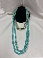 Both long beaded necklaces draped on display bust