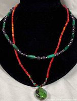 Both necklaces displayed on black bust