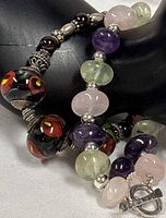 Both bracelets draped on display hand showing bead types and silver spacers