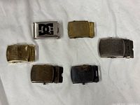 All six buckles laid out showing variety of finishes