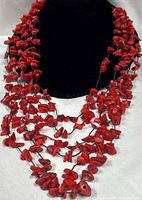 Close view of multi-strand red coral chip necklace on bust