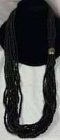 Front view of entire multi-strand black bead necklace on bust, showing focal sterling bead