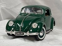 Front three-quarter view of green 1951 VW Beetle model showing license plate and headlights