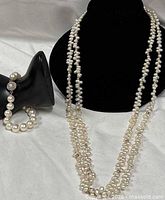 Necklace draped on bust form and bracelet on display hand