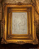 Full view of framed white relief plaque showing ornate gilt frame and artwork