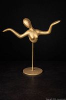 Full view of gold-tone ceramic abstract female torso sculpture on rod and circular base