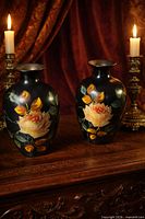 Both vases side by side on wooden surface with candles behind