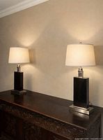 Both matching black and brushed metal table lamp bases on wooden sideboard