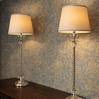 Two matching metal and glass table lamps on wood surface