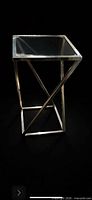 Full view of chrome frame side table with glass top against dark background