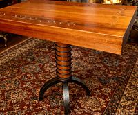 Full view of table showing wood slab top, spring-wrapped column, wrought iron base