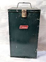 Front view of Coleman metal case showing overall form, color, and logo