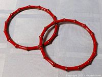 Two red enamel bamboo-style metal bangles on fabric