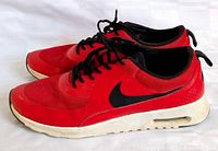 Side view of pair showing red uppers, black swoosh, white midsole with air unit