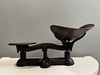 Full side view of balance scale showing both pans and base