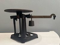 Full view of cast-iron mercantile scale showing base, platform, beam and weight