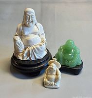 White resin Buddha on stand with green and small cream Buddhas