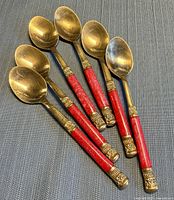 Six brass spoons arranged fan-style showing bowls and handles