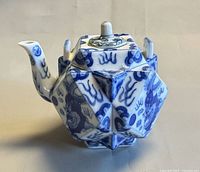 Front and side view of blue and white faceted porcelain teapot showing spout and dragon motif