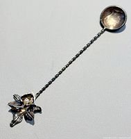 Full view of spoon showing coin bowl and orchid finial