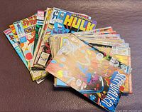 Stack of approximately 25 Marvel comics fanned on leather surface