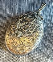 Front of locket showing engraved floral and lattice design, bail attached