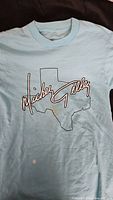 Front of light blue Mickey Gilley concert T-shirt