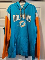 Front view of teal and orange Miami Dolphins hoodie showing graphics and pocket