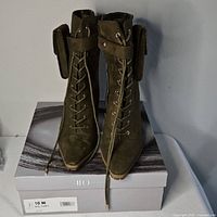 Front view of olive green lace-up ankle boots on original box