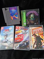 Five games including NES cartridge, PlayStation case, two Switch cases, PSP case