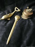 Group shot of dolphin bottle opener, shell letter opener, and swan bell