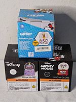 Front view of three boxed Disney mini snow globes showing artwork and labels