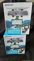 Two boxed Merkury Rearview Mirror Phone Mounts front view
