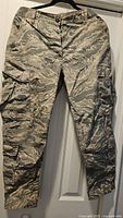 Full front view of U.S. Air Force tiger-stripe camouflage cargo pants hanging