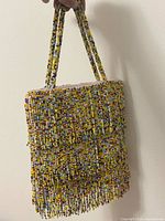 Front view of multicolour seed bead purse with fringe and handles