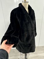 Front view of black faux fur coat on dress form