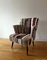 Front left view of upholstered armchair showing patterned fabric and wooden legs