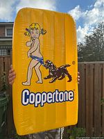 Full view of inflatable Coppertone display held upright outdoors