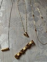 Four jewellery items laid out: three necklaces and one bracelet