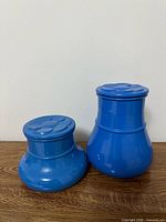 front view of both blue glass canisters showing size difference and lids