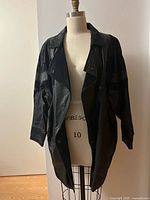 Front view of black paneled leather and suede coat on dress form
