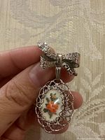 Front view showing bow, filigree frame, floral needlepoint insert