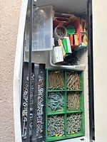 Overview of drawer showing green divided bins of screws/bolts, washers/nuts, perforated steel bars and upper basket of fasteners