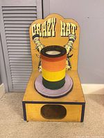 Front view of Crazy Hat game showing hat cylinder and retrieval opening