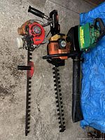 All three yard tools—Kawasaki hedge trimmer, Stihl hedge trimmer, Weed Eater leaf blower—grouped on floor