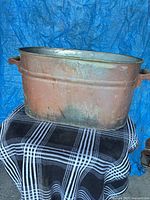 Front view of oval copper tub showing rolled rim and one metal handle