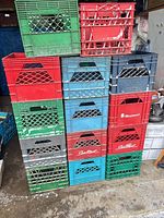 Stack of mixed-colour plastic milk crates, showing quantity and fronts