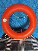 Front view of orange life ring showing full shape and grab rope
